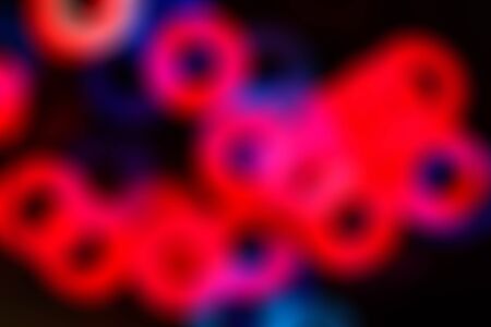 Blurred abstract background with colored rings on a dark backdrop.の写真素材