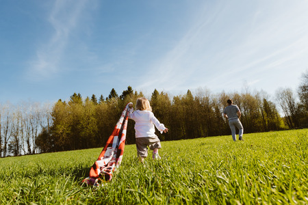 Little girl with a blanket follows his father in the parkの写真素材