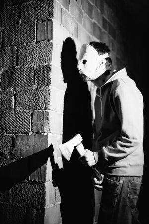 Maniac with an ax to expect the victim near a brick wall. Black and white photo close-up.の写真素材