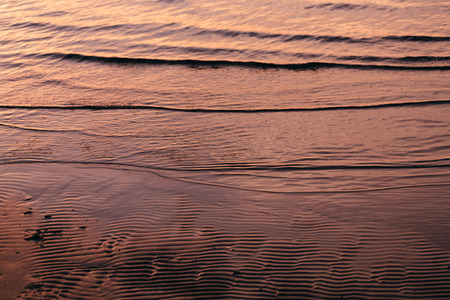 tide water to the sandy shores of the evening close-upの写真素材