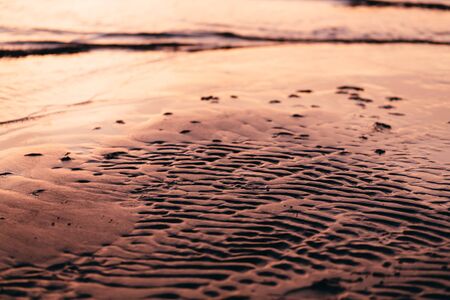 tide water to the sandy shores of the evening close-upの写真素材