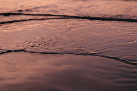 tide water to the sandy shores of the evening close-upの写真素材