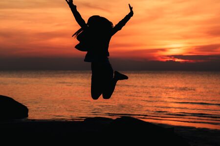 Happy girl jumping against beautiful sunset. Freedom, enjoyment concept.の写真素材