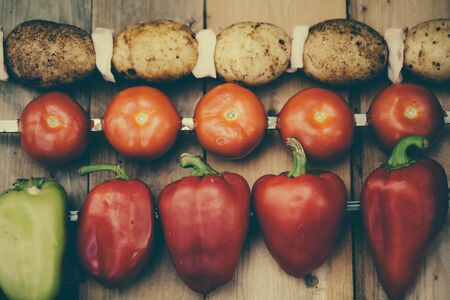 Vegetables on a skewer. Tomatoes. Bell peppers red and green. Potatoes with bacon ready for roasting on a fire. Top view.の写真素材