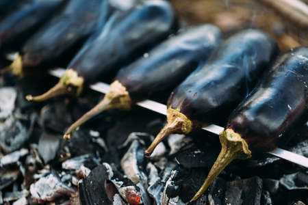 Eggplant on a skewer roasting on coals. Cooking eggplant charcoal closeup.の写真素材