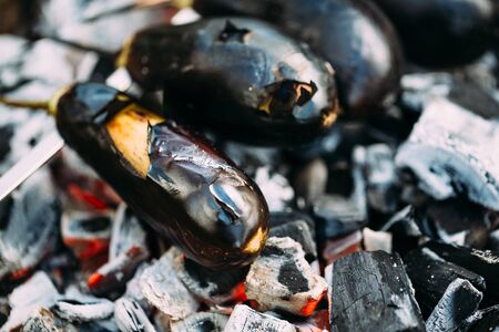 Eggplant on a skewer roasting on coals. Cooking eggplant charcoal closeup. Top view.の写真素材