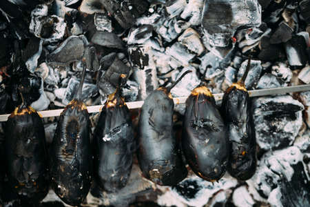 Eggplant on a skewer roasting on coals. Cooking eggplant charcoal closeup. Top view.の写真素材