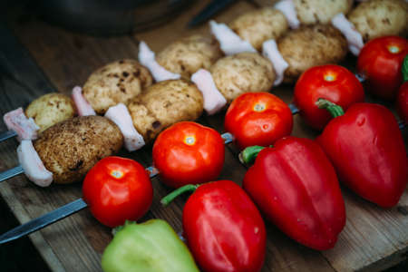 Tomatoes pepper potato with bacon on skewers ready for cooking.の写真素材