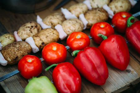 Tomatoes pepper potato with bacon on skewers ready for cooking.の写真素材