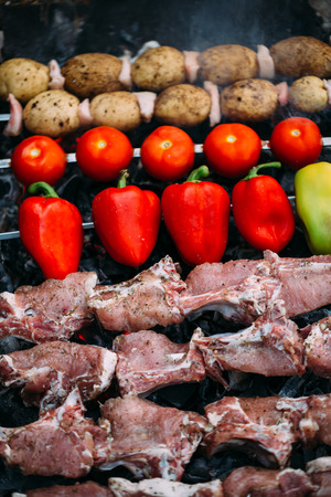Meat and vegetables are roasted on coals. Bell pepper, potato, tomato and meatの写真素材