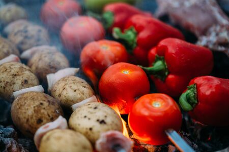 Meat and vegetables are roasted on coals. Bell pepper, potato, tomato and meatの写真素材
