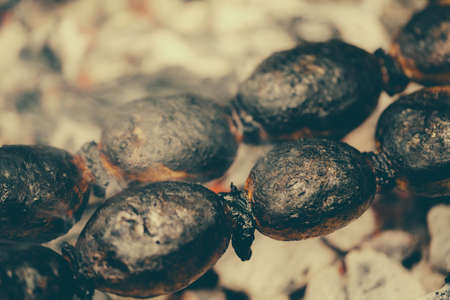 Baked potato with bacon on skewers. barbeque potatoes closeup on coals, mangal.の写真素材