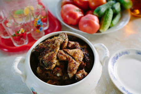 Fried chicken wings on the table against the background of cucumbers and tomatoes.の写真素材