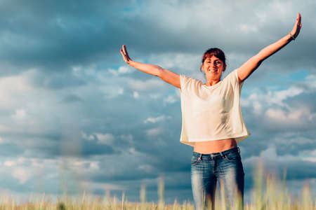 Happy beautiful brunette girl jumping into the field against the sky.の写真素材