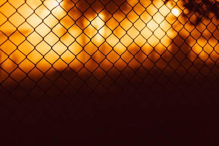 Mesh fence close-up on a blurred background of orange and brown.の写真素材