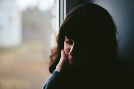 Young woman longs near a window close up photo.の写真素材