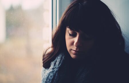Young woman longs near a window close up photo.の写真素材