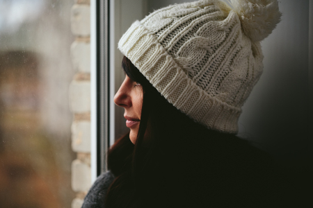 Girl in a cap looks out of the window closeup photo.の写真素材