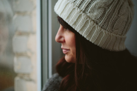 Girl in a cap looks out of the window closeup photo.の写真素材