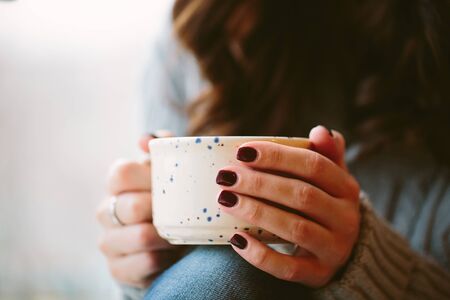 Close up of a  young woman hands holding a cup of hot coffee.の写真素材