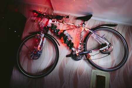Bicycle on a wall decoration of the christmas lamp garland close up photo.の写真素材