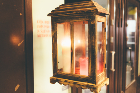 Burning candle in a glass box on the street before an institution at night. Closeup photo.の写真素材