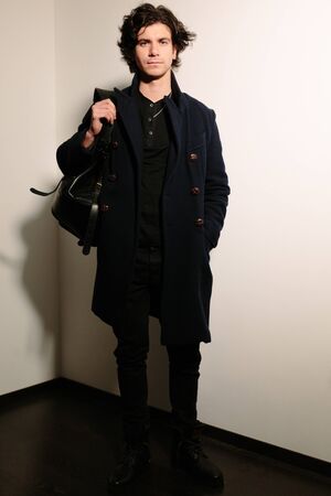 Handsome young man in a black coat with a black bag.の写真素材
