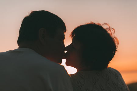 Adult married couple kiss against a sunset. Close up photo.の写真素材