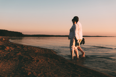Adult couple walks on the seashore. Back view.の写真素材
