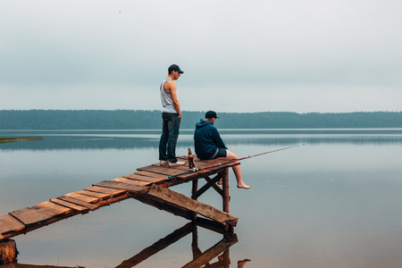 Two men are waiting on a wooden bridge when the fish are biting. Weekend photo.の写真素材