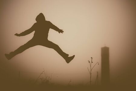 Silhouette of the jumping person in the evening. Outdoors photo.の写真素材