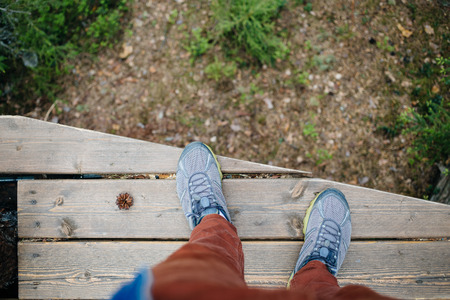 Man looking down on the leaves standing on a wooden bridge. Pov photo at daytime.の写真素材