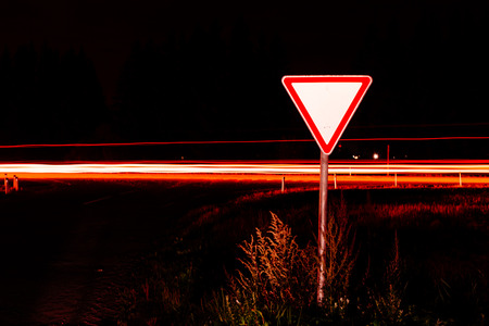 Road sign give way. Road sign at night on the background traffic at long exposure.の写真素材