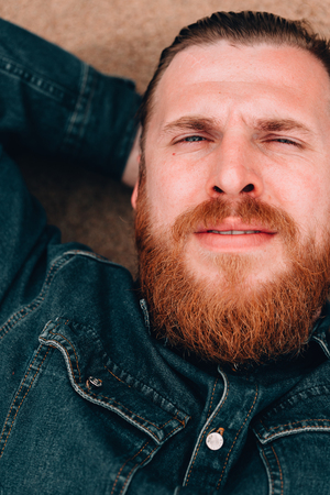 Pensive dreams hipster bearded man lying on the sand beachの写真素材
