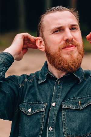 Handsome bearded man straightens your hair. bearded hipster on the beachの写真素材