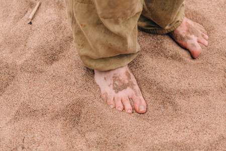 Barefoot male legs on sand beach closeupの写真素材
