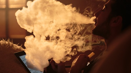 young man smokes a hookah and uses tablet