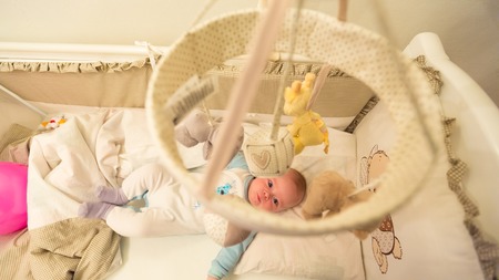 Baby lying in his cot and playing with Crib Mobiles. top view