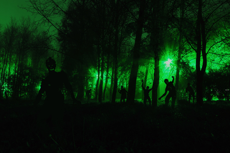 crowd of hungry zombies in the woods. Silhouettes of scary zombies walking in the forest at nightの写真素材