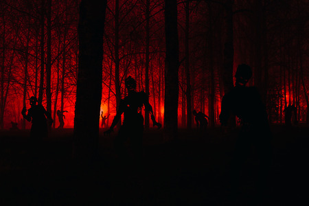 crowd of hungry zombies in the woods. Silhouettes of scary zombies walking in the forest at nightの写真素材