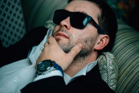 Business man in sunglasses is resting on the couchの写真素材