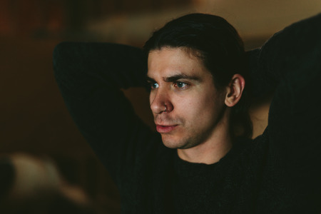 Portrait of the young long-haired brunette Man on a dark background
