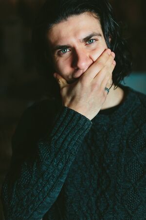 Portrait of the young long-haired brunette Man on a dark background