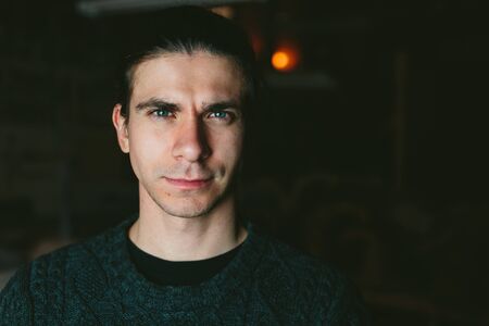 Portrait of the young long-haired brunette Man on a dark backgroundの写真素材