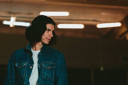 Young handsome man with long hair brunette in a denim jacketの写真素材