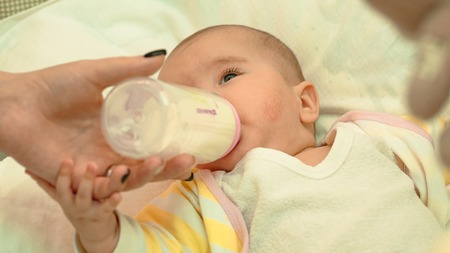 Little newborn baby drinking milk from a bottle close-upの写真素材