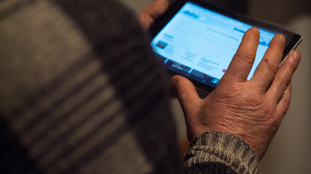 Tablet computer in the hands of an elderly man close up. view from the backの写真素材