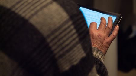 Tablet computer in the hands of an elderly man close up. view from the back