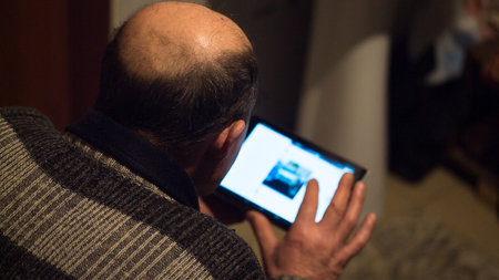 Tablet computer in the hands of an elderly man close up. view from the backの写真素材