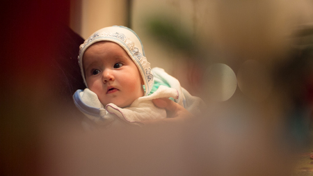Little baby with his grandmother on his knees at the table